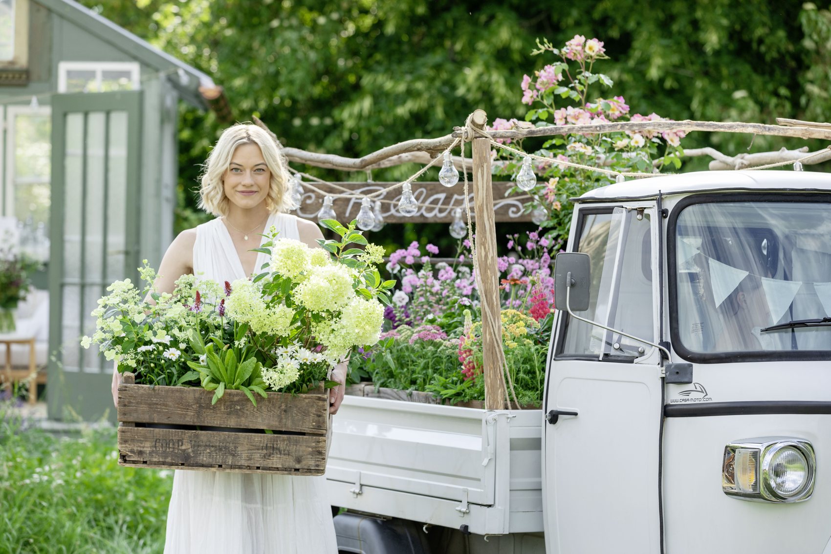 Frau mit weißem Lieferwagen voller Gartenblumen